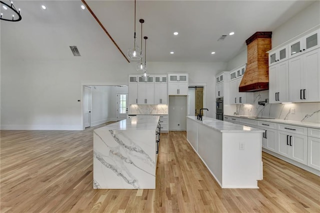 kitchen with a spacious island, sink, hanging light fixtures, and white cabinets