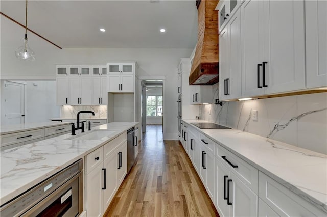 kitchen with sink, white cabinetry, hanging light fixtures, black electric stovetop, and light stone countertops