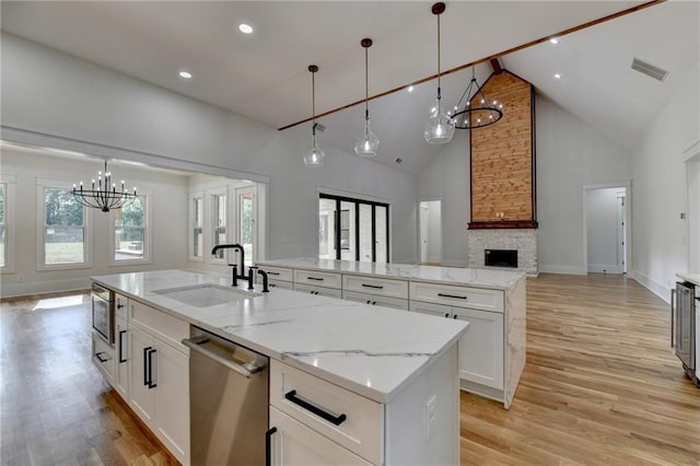 kitchen featuring a kitchen island with sink, pendant lighting, white cabinets, and appliances with stainless steel finishes