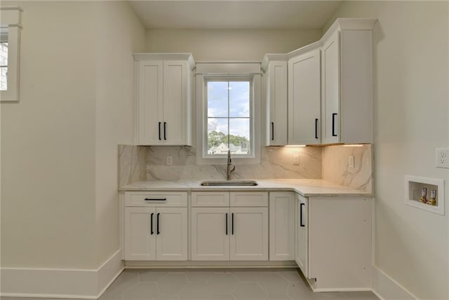 kitchen with light tile patterned floors, sink, decorative backsplash, and white cabinets