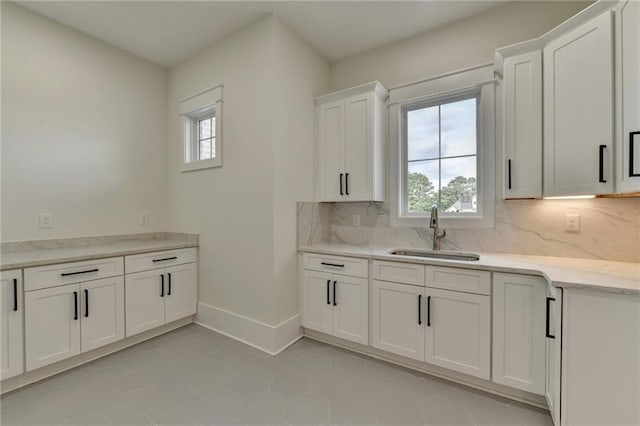 kitchen with sink, decorative backsplash, light tile patterned floors, and white cabinets