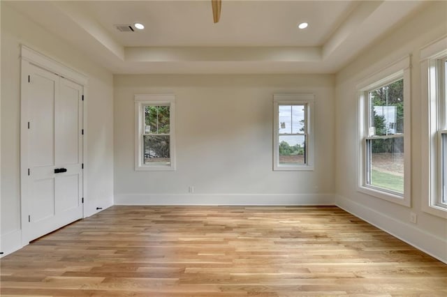 empty room featuring a raised ceiling and light wood-type flooring