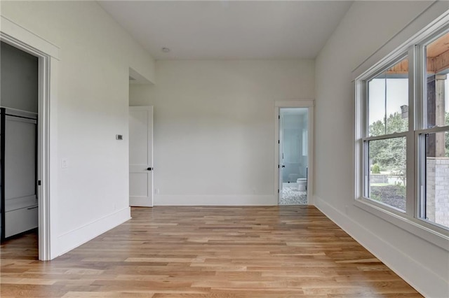 unfurnished bedroom featuring ensuite bath and light hardwood / wood-style floors