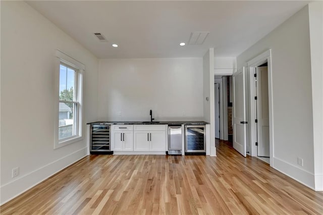 kitchen featuring white cabinetry, sink, wine cooler, and light wood-type flooring