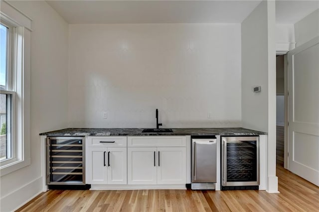 bar with white cabinets, sink, wine cooler, and light hardwood / wood-style flooring