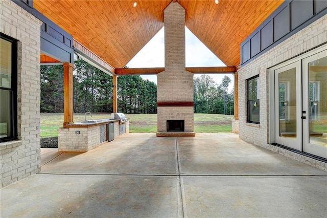 view of patio with an outdoor brick fireplace, sink, area for grilling, and a grill