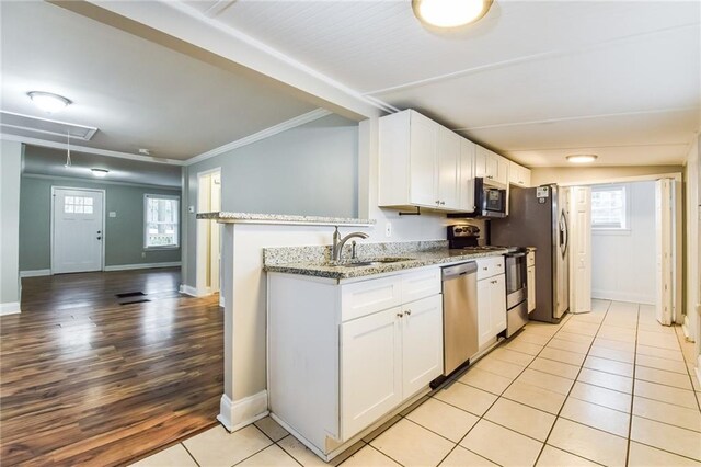 kitchen with a healthy amount of sunlight, light stone countertops, white cabinetry, and appliances with stainless steel finishes