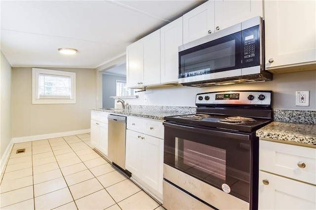 kitchen with light stone countertops, appliances with stainless steel finishes, light tile patterned floors, and white cabinetry