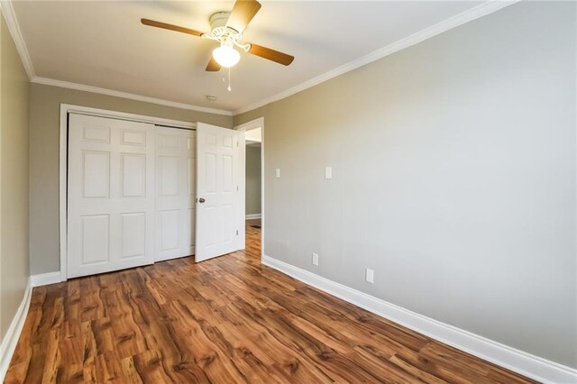 unfurnished bedroom with a closet, hardwood / wood-style flooring, ceiling fan, and crown molding