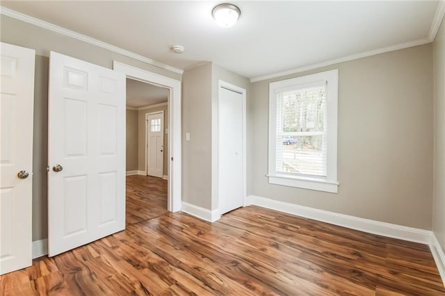 unfurnished bedroom featuring wood-type flooring, crown molding, and a closet