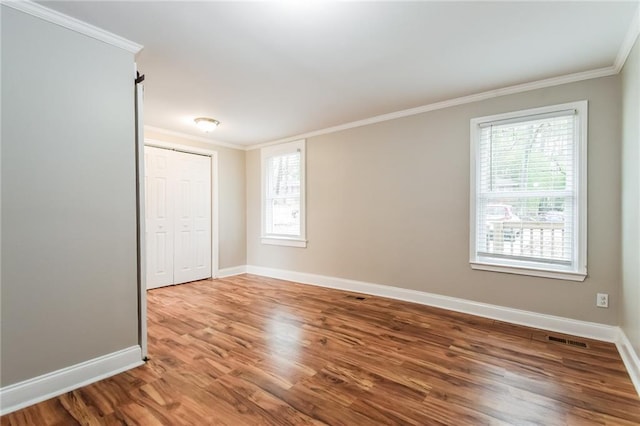 unfurnished room featuring a wealth of natural light, hardwood / wood-style flooring, and ornamental molding