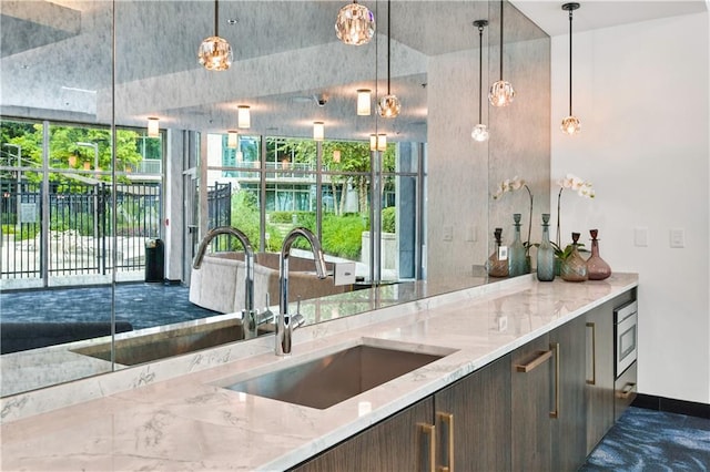 950 W Peachtree St NW Unit 904, Atlanta, GA 30309 - kitchen featuring a sink, light stone counters, pendant lighting, and dark brown cabinets