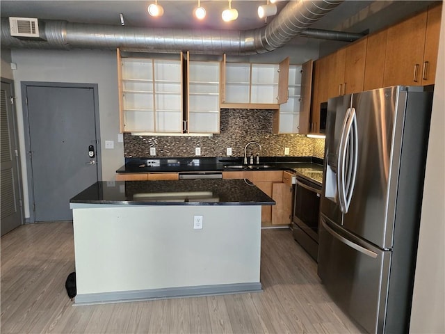 kitchen with sink, appliances with stainless steel finishes, a kitchen island, and light hardwood / wood-style floors