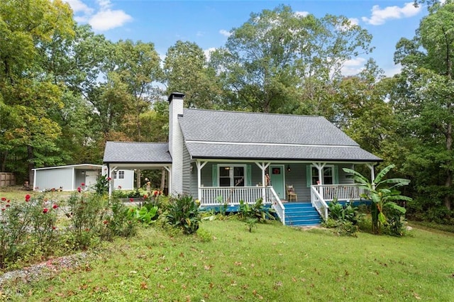 view of front facade with covered porch, an outbuilding, and a front lawn