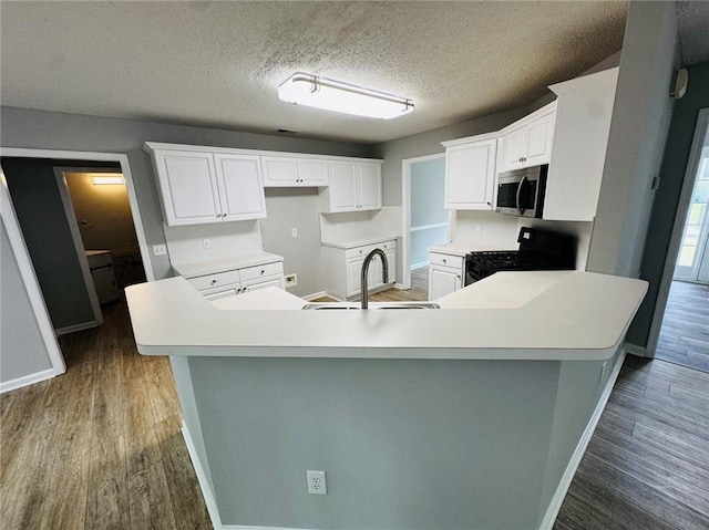 108 Northcutt Station Pl, Acworth, GA 30101 - kitchen featuring black gas stove, stainless steel microwave, baseboards, wood finished floors, and a textured ceiling