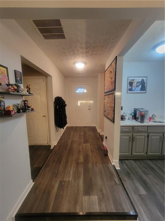 hallway with dark hardwood / wood-style flooring, sink, and a textured ceiling