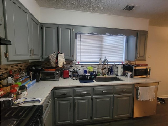 kitchen featuring tasteful backsplash, appliances with stainless steel finishes, sink, and gray cabinets