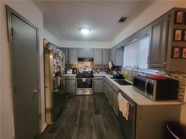 kitchen with stainless steel appliances, sink, decorative backsplash, and gray cabinetry