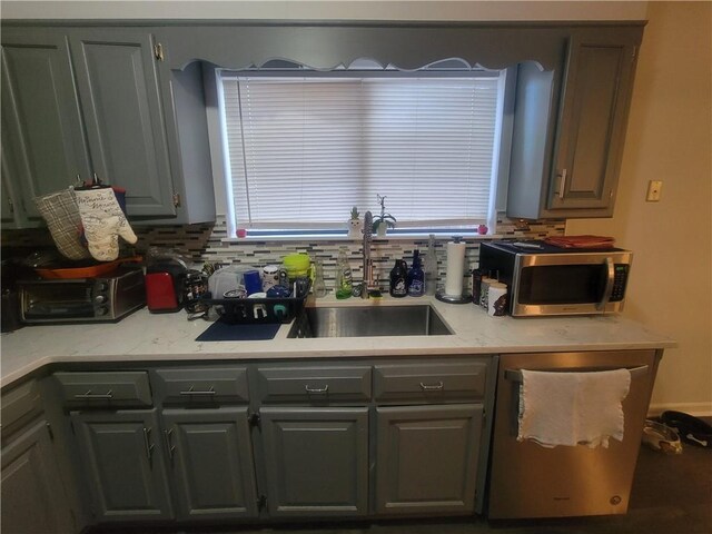 kitchen featuring appliances with stainless steel finishes, dark wood-type flooring, gray cabinetry, and decorative backsplash