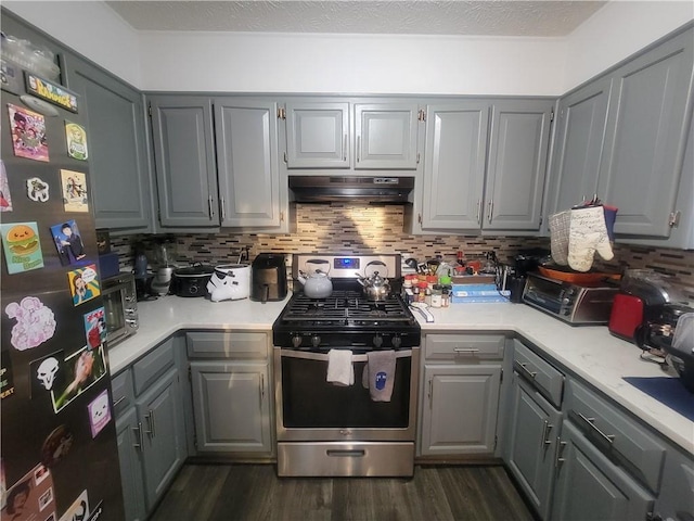 kitchen featuring gray cabinets, stainless steel appliances, dark wood-type flooring, under cabinet range hood, and tasteful backsplash