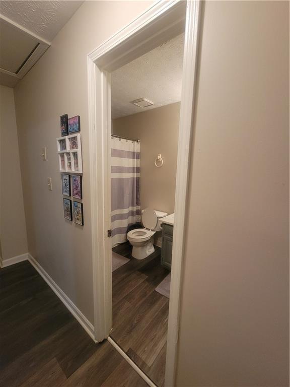 corridor featuring dark hardwood / wood-style flooring and a textured ceiling