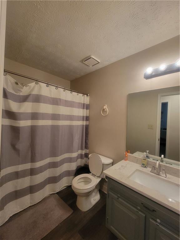 bathroom featuring vanity, hardwood / wood-style flooring, toilet, and a textured ceiling