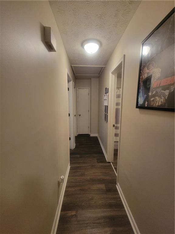 hallway featuring baseboards, dark wood-type flooring, and a textured ceiling