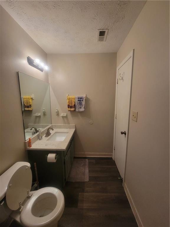 bathroom featuring vanity, wood-type flooring, a textured ceiling, and toilet