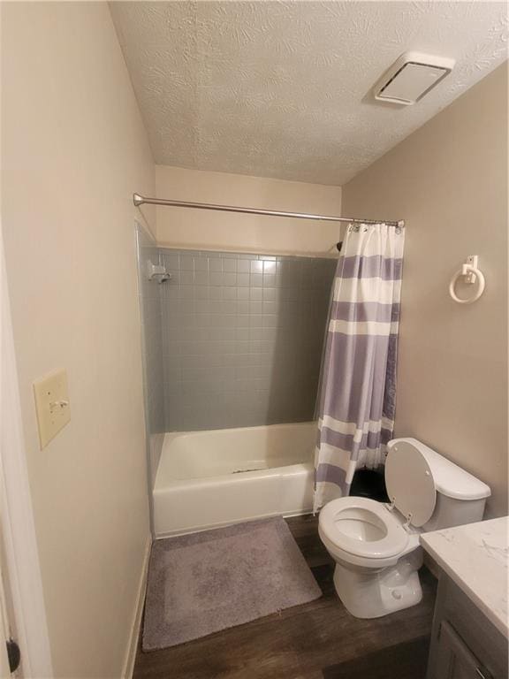 bathroom featuring visible vents, toilet, vanity, wood finished floors, and a textured ceiling