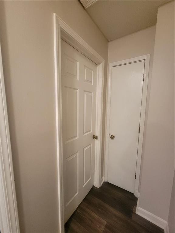 hall featuring baseboards and dark wood-type flooring