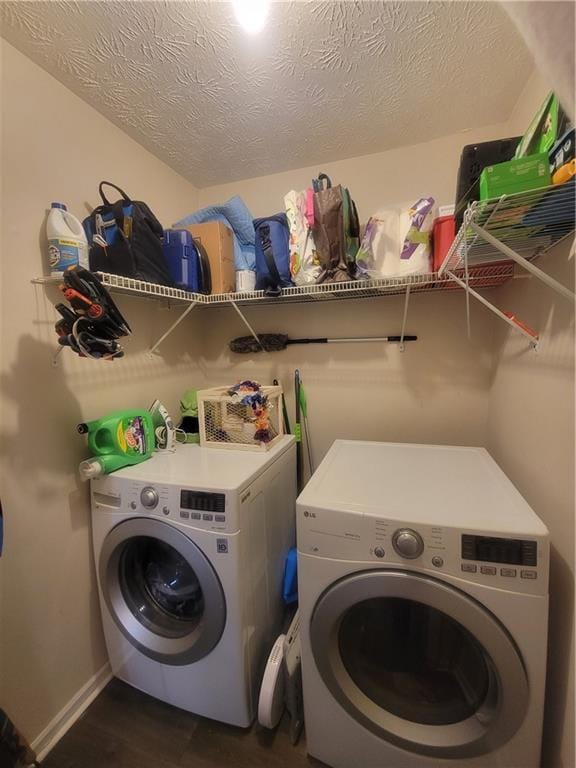 clothes washing area with washing machine and clothes dryer and a textured ceiling