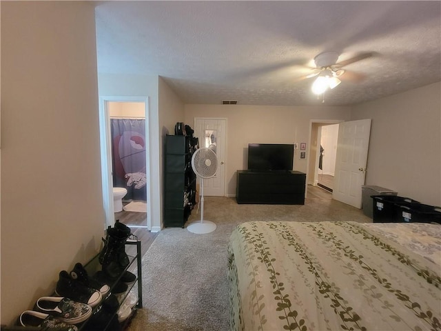 carpeted bedroom featuring ensuite bath, a walk in closet, ceiling fan, a textured ceiling, and a closet