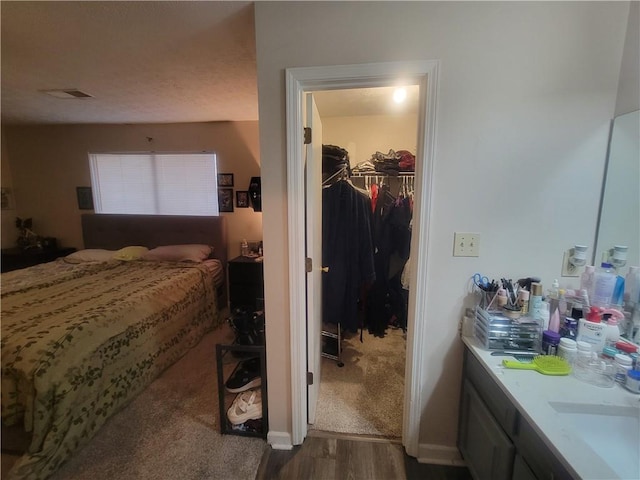 bedroom with a walk in closet, dark hardwood / wood-style flooring, sink, and a closet