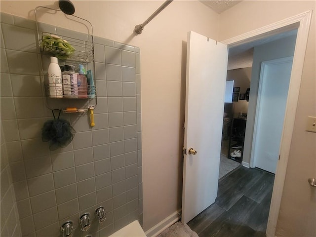 bathroom featuring wood finished floors, baseboards, and walk in shower