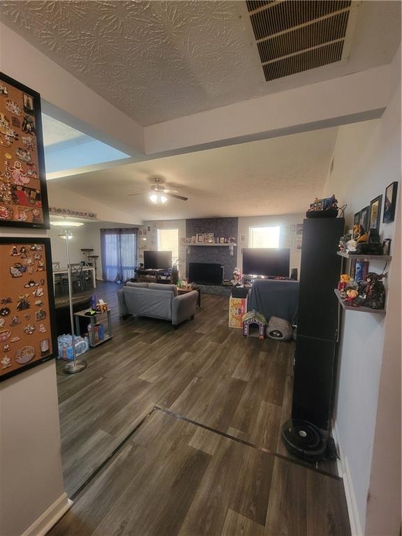 living room featuring ceiling fan, a fireplace, and dark hardwood / wood-style flooring