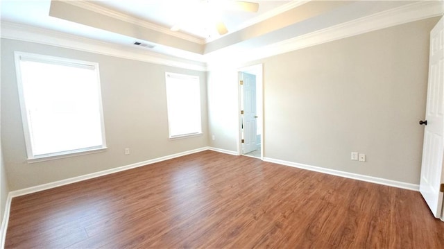 empty room with crown molding, a ceiling fan, wood finished floors, and visible vents