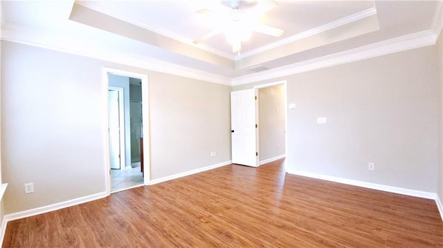 unfurnished room with ceiling fan, crown molding, wood finished floors, baseboards, and a tray ceiling