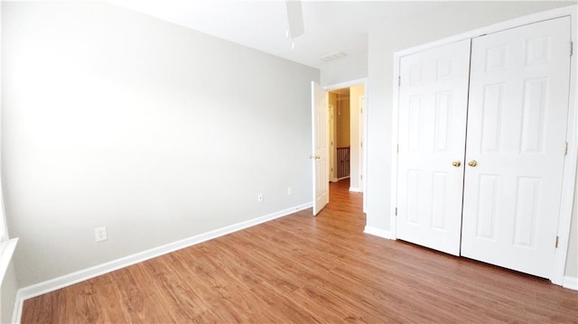 unfurnished bedroom featuring baseboards, ceiling fan, a closet, and light wood finished floors