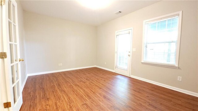 empty room with visible vents, baseboards, and wood finished floors