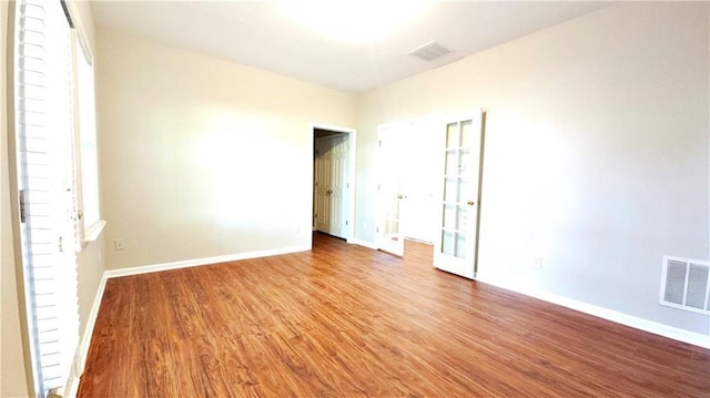 empty room featuring baseboards, visible vents, and wood finished floors