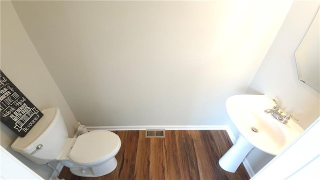 bathroom featuring a sink, toilet, baseboards, wood finished floors, and visible vents