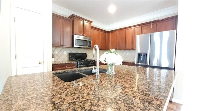 kitchen with decorative backsplash, stainless steel appliances, ornamental molding, and a sink
