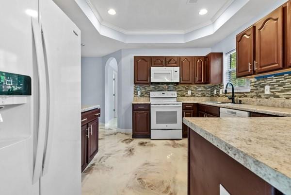 kitchen with white appliances, a tray ceiling, light countertops, a sink, and ornamental molding