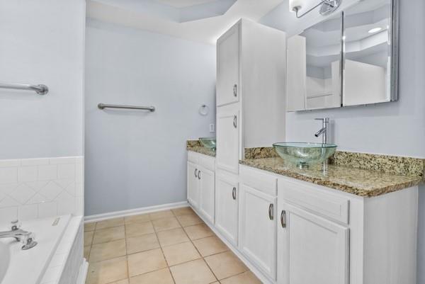 bathroom featuring a bath, vanity, tile patterned floors, and baseboards