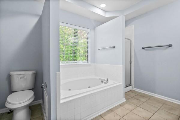 full bath with toilet, a shower stall, a whirlpool tub, baseboards, and tile patterned floors