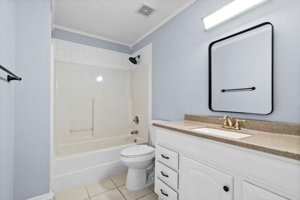 bathroom with crown molding, tile patterned floors, toilet, vanity, and shower / bath combination