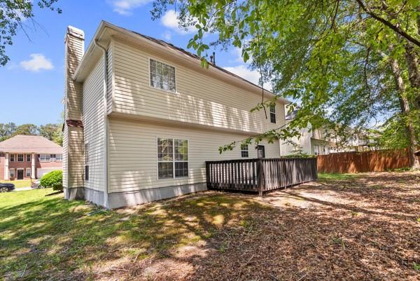 rear view of property featuring a chimney, a deck, and fence