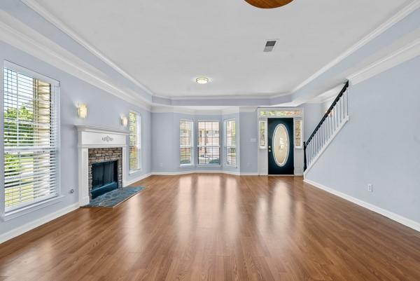 unfurnished living room featuring baseboards, wood finished floors, ornamental molding, and a fireplace