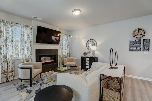 living room with a tile fireplace and light hardwood / wood-style floors