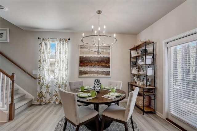 dining space with light hardwood / wood-style floors and a chandelier